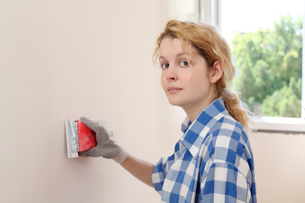 Een persoon gebruikt een zachte borstel om voorzichtig spachtelputz schoon te maken, waardoor de textuur behouden blijft en de muur fris oogt.