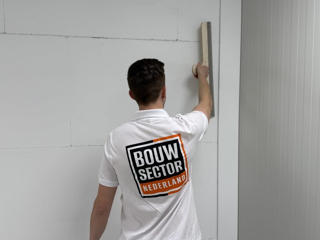 Stukadoor van Bouwsector Nederland zet een brede spaan tegen een naad in de wand