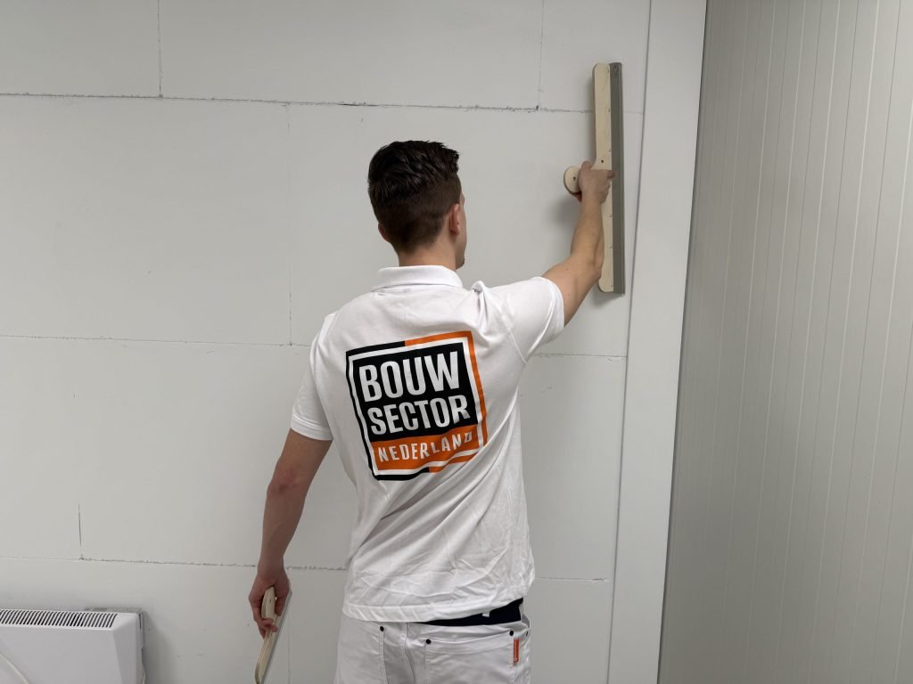 Stukadoor van Bouwsector Nederland werkt met een brede spaan een naad in de wand af